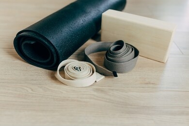 yoga equipment, black mat, brick, belts laid out on the floor in the studio