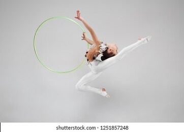 the teen female little girl doing gymnastics exercises with hoop isolated on a gray studio background. the gymnastic, stretch, fitness, lifestyle, training, sport concept