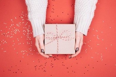 gift box with bow in woman's hands. living coral - color of the year 2019.