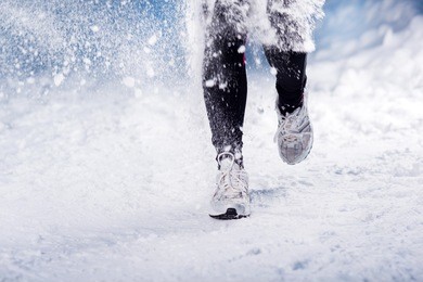 athlete woman is running during winter training outside in cold snow weather.