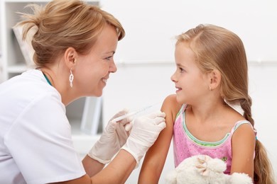 brave little girl receiving injection or vaccine with a smile