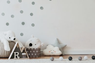 stylish scandinavian newborn baby interior with mock up photo poster frame on the pattern wall, boxes, teddy bears and toys. white walls, wooden accessories and toys. copy space.