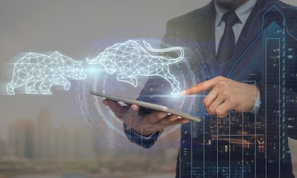 double exposure of businessman using the tablet with virtual reality technology showing polygonal bull and bear shape for trading information over cityscape and financial graph background