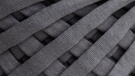 skein of gray knitted yarn close-up. macro photography background texture pattern weave fiber textile fabric. strips of fabric are interwoven on a reel.