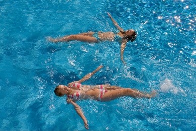 teenage girls having fun in outdoor swimming pool on summer vacation