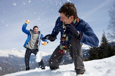 young men having snowball fight in snow on winter vacation