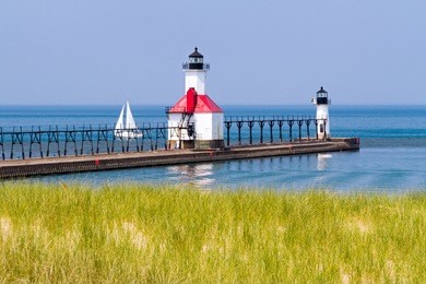 st. joseph, michigan north pier lighthouses with a sailboat on lake michigan.