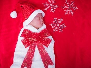 newborn baby sleeping on santa het and red background, christmas or happy new year concept