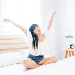 an asian woman is sleeping in bed. this is a lazy lifestyle.