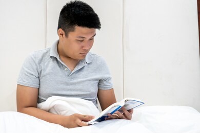asian man reading book before go to bed