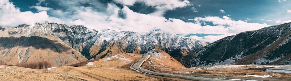 stepantsminda, gergeti, georgia. famous gergeti trinity tsminda sameba church in early winter panoramic landscape. panorama of beautiful georgian mountains landscape.