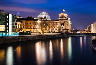 illuminated neo-renaissance  reichstag building, one of the best known landmarks of germany and seat of the german parliament as viewed from across the spree river at night, central berlin, germany