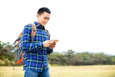 young man enjoy hiking trip and browsing his phone