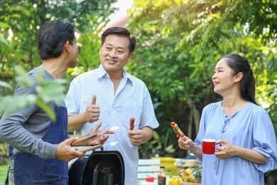senior friends have barbecue party in the park.
