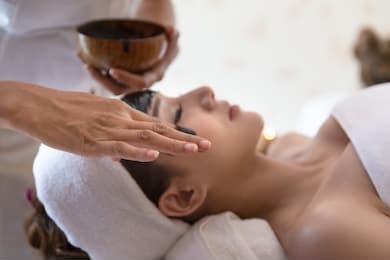 selective focus of masseur hand which relaxing in spa salon of young woman getting spa treatment at beauty salon,spa face massage,facial beauty treatment in spa salon.