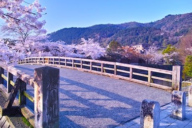 kyoto arashiyama where spring cherry blossoms, nakanoshima bridge hanging on katsura river. in the lower left corner of the photo, the name of "katsura river" kanji is engraved.