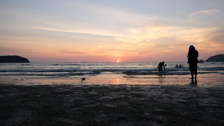 一位年轻女性在日落时站在泰国甲米奥南海滩享受假期