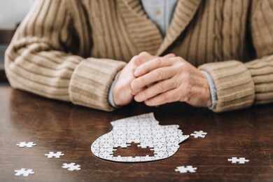 cropped view of senior man playing with puzzles on table