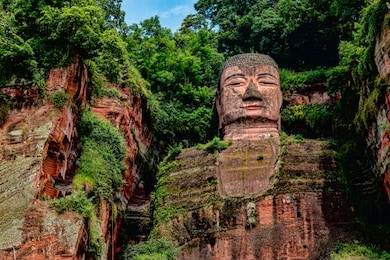 dark colorful view of leshan giant buddha in sichuan province, china. ancient stone sculpture carving in cliff face.