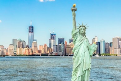 lady liberty standing in front of manhattan skyline