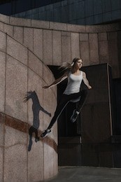young sporty woman doing parkour in city. the girl is engaged in freerunning.
