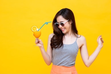 happy asian woman in summer casual clothes with a glass of fresh fruit juice drink studio shot isolated on colorful yellow backgroud
