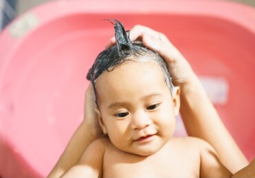 portrait of a asian baby is being bathed and shampooed by his mother.selective focus