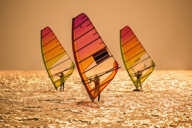 silhouette sportsman is windsurfing at sunset time on wind of wave at jomtien beach, thailand