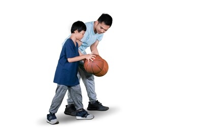 little boy learning to dribble a basketball with his father while exercising in the studio, isolated on white background