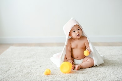 baby in a bath towel with rubber ducks