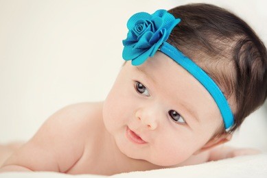 little girl lying on a white cover with blue flower color