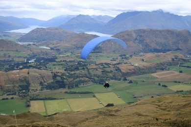 paragliders in flight above the queenstown countryside. south island. new zealand