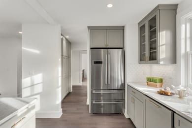 kitchen detail in newly remodeled home: hardwood floors, stainless steel refrigerator, and quartz counters
