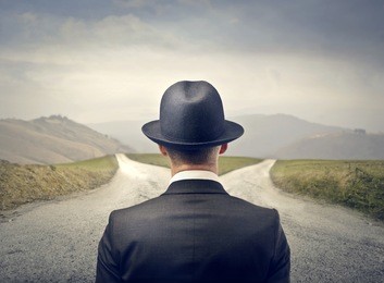 businessman with hat in front of two roads