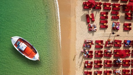 aerial drone top view photo of iconic beach of super paradise with emerald clear sandy organised beach with sun beds and umbrellas and traditional fishing boat, mykonos island, cyclades, greece