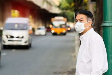 a man wearing mouth mask against air smog pollution with pm 2.5 in bangkok city, thailand. 