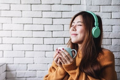 young woman listening music from headphone in cozy house, closed eyes and relaxing in happiness moment