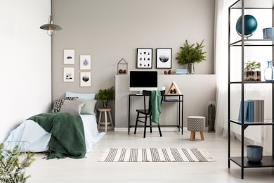 silver, green and patterned pillow on blue bedding on single bed with green blanket in modern forest inspired bedroom, real photo with copy space