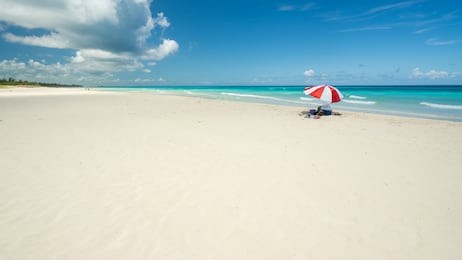 nice  beach of varadero during a sunny day, fine white sand and turquoise and green caribbean sea,on the right one red parasol,cuba.concept  photo,copy space.
