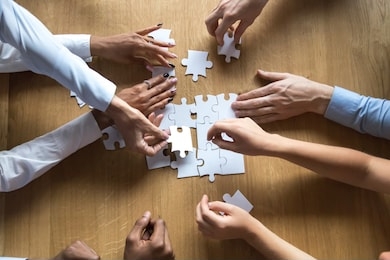above top view to the hands of diverse people assembling connecting jigsaw puzzle associates put pieces searching common solutions making right decisions together. support and help in business concept