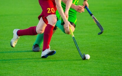 two man battle for control of ball during field hockey game