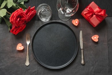 valentine's day or birthday romantic dinner. elegance table setting with red rose on black linen tablecloth.