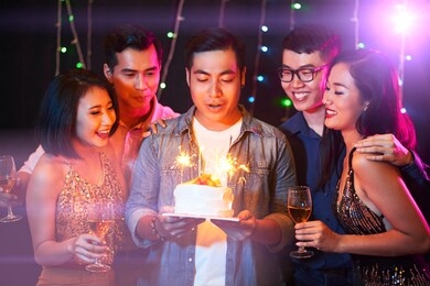 group of happy friends at birthday party of young man in night club