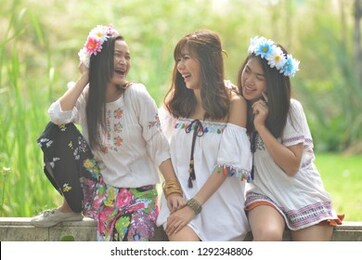 three asian teenage girls dressed in fashion style, bohemians are doing a smiling way. hugging, teasing a close friend