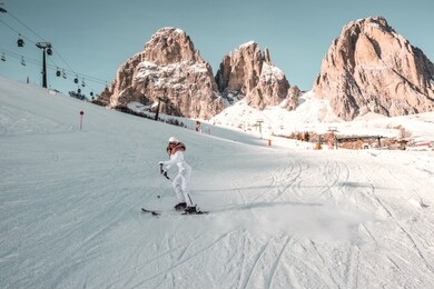 snowy white winter day in high mountains. woman in fashionable jacket with fur, ski goggles and helmet. girl skiing.
