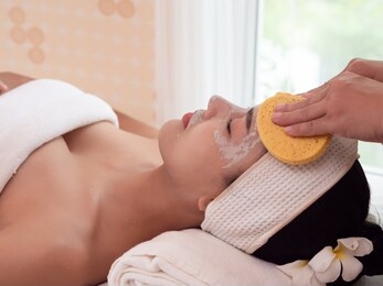 masseuse cleaning young asian woman face with sponge swabs at spa. beauty treatments