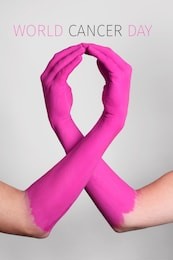 closeup of the arms of two people painted pink forming a pink awareness ribbon for the breast cancer awareness, and the text world cancer day