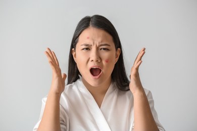 portrait of stressed asian woman with acne problem on white background