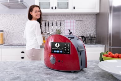 happy woman looking at red toaster with voice recognition function on kitchen counter