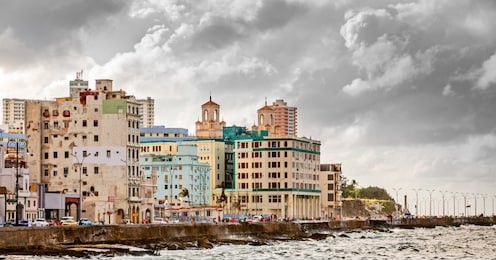 malecon street embankment and atlantic ocean waves, with colorful havana city in the background with grey clouds, cuba